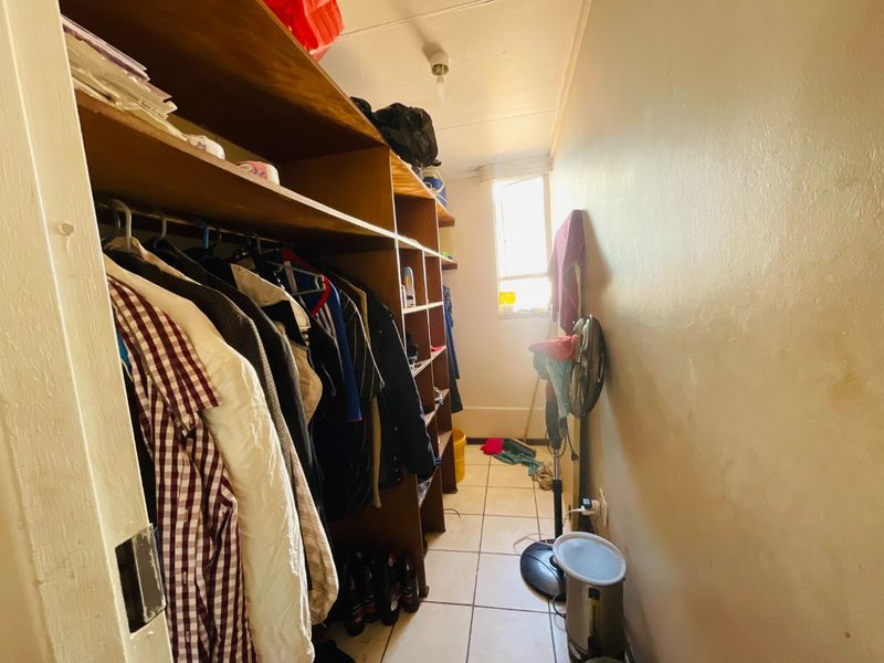 A narrow utility or storage room featuring built-in wooden shelving and tiled flooring, providing functional space for organization.