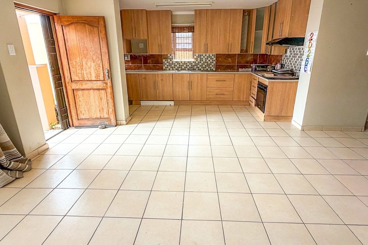 A functional kitchen featuring wooden cabinetry, built-in oven, extractor fan, and tiled flooring, offering a clean and practical layout for culinary activities.