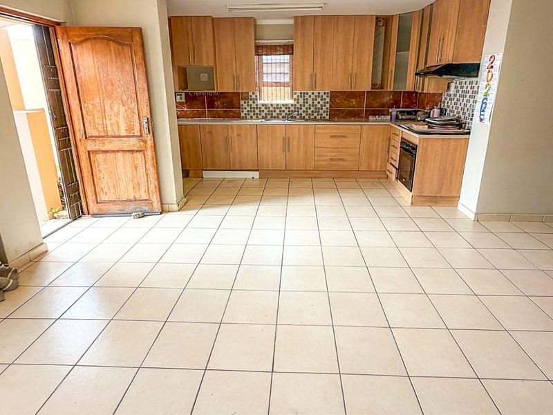 A functional kitchen featuring wooden cabinetry, built-in oven, extractor fan, and tiled flooring, offering a clean and practical layout for culinary activities.