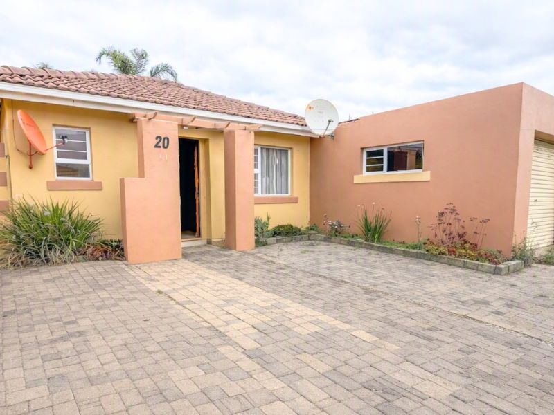 Front elevation of a single-story house featuring a paved driveway, attached garage, and tiled roof.