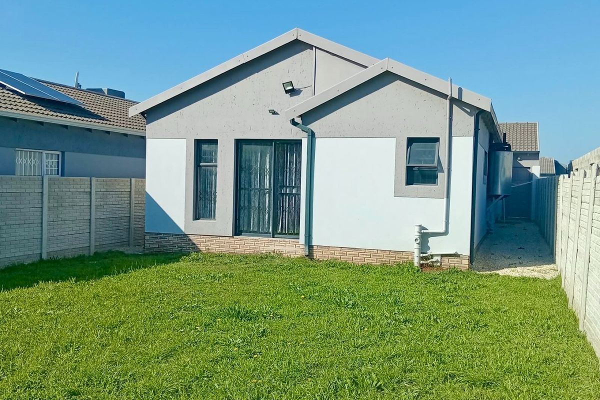 Rear view of the property featuring a private garden, sliding door access, and secure precast concrete boundary walls.