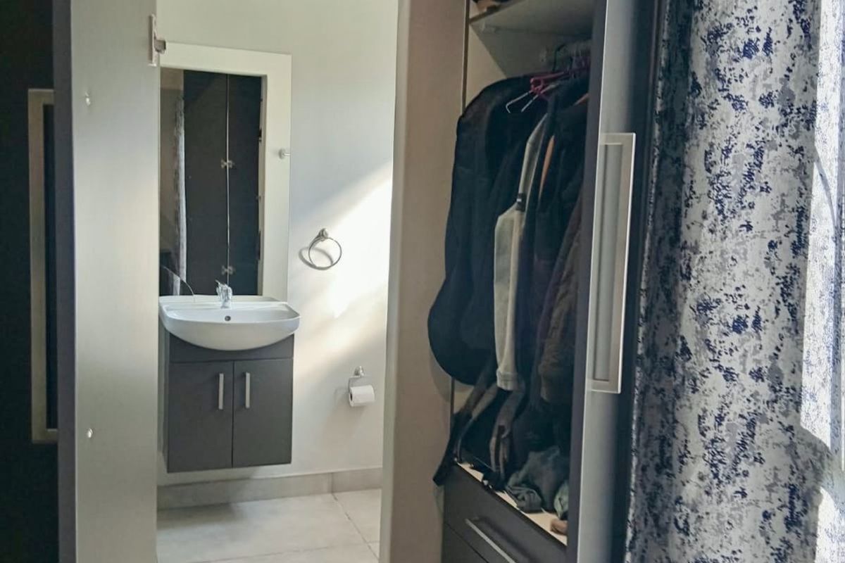 A functional bathroom featuring a modern vanity cabinet and basin, adjacent to a built-in wardrobe storage area with tiled flooring throughout.