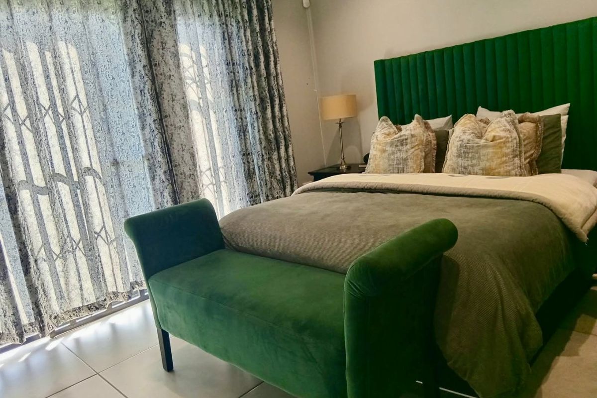 A well-maintained bedroom featuring tiled flooring and a sliding glass door with an integrated security gate, providing direct access to the outdoors.