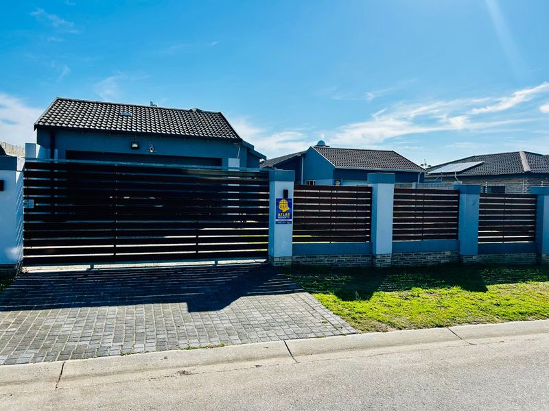 Front view of the property featuring a modern sliding gate, slatted timber fencing with brick pillars, and a paved driveway.