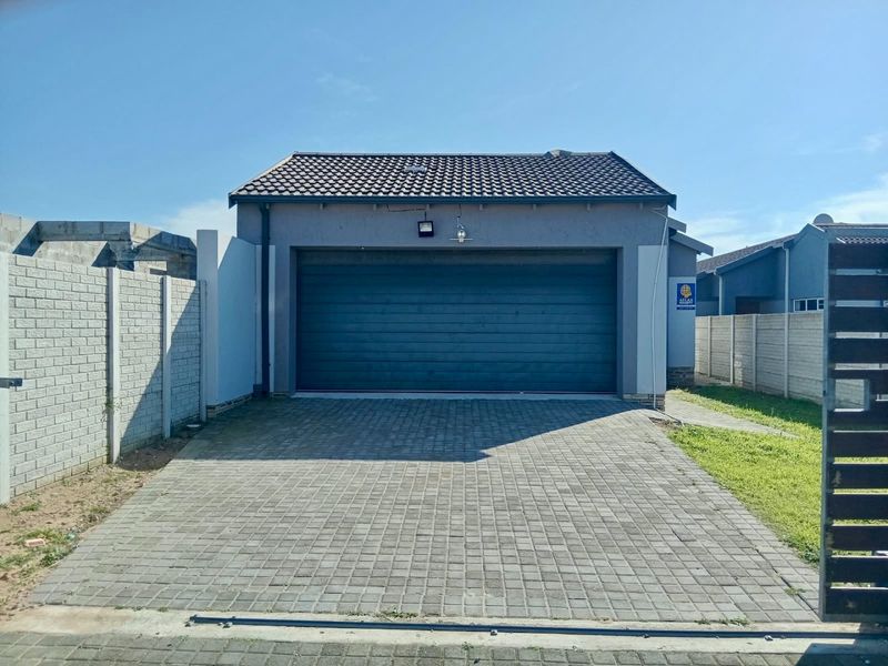 A well-maintained single garage featuring a tiled roof, automated door, and a neat paved driveway, enclosed by precast concrete boundary walls.
