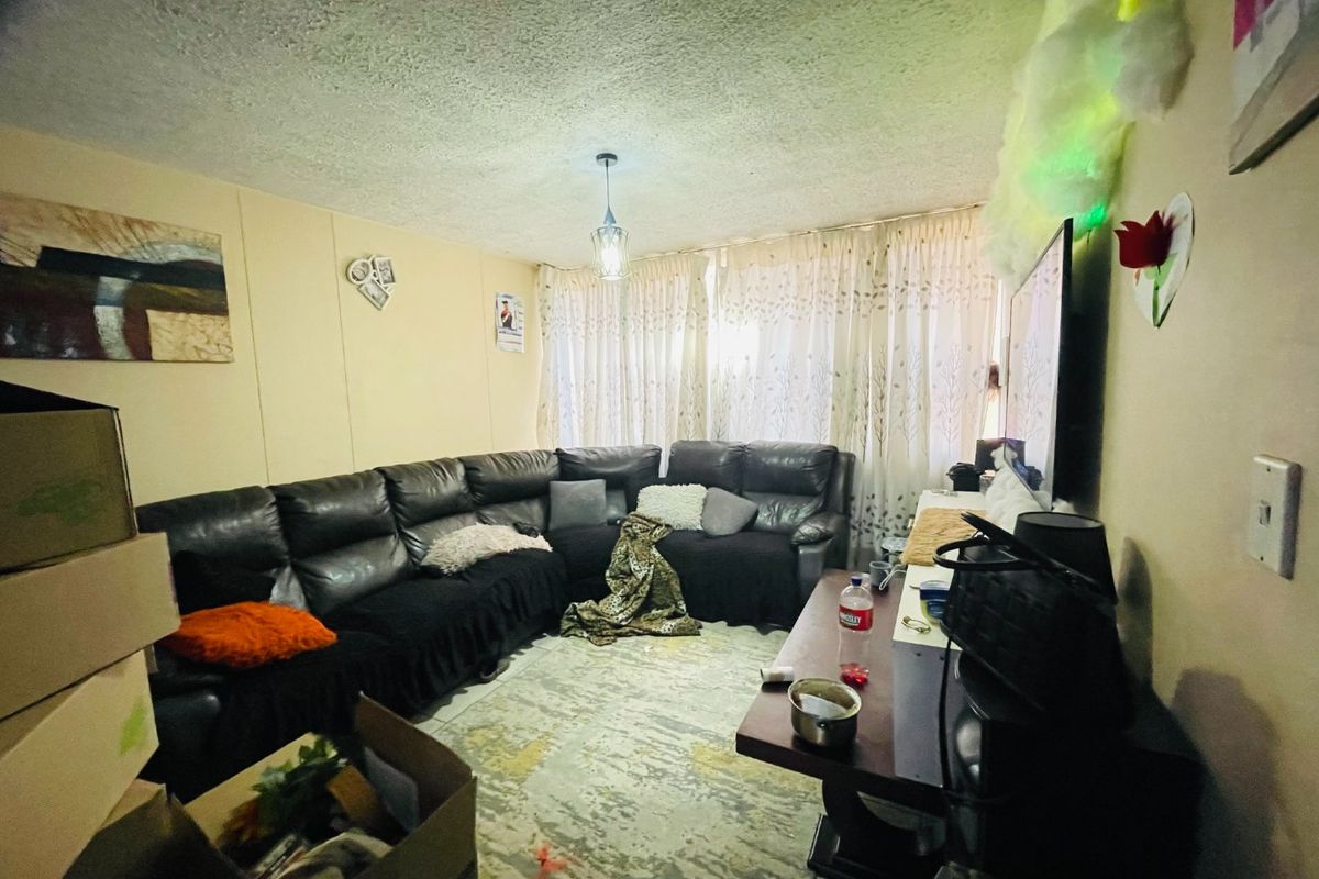 A living room space featuring textured ceilings and window treatments, currently utilized as a lounge area.