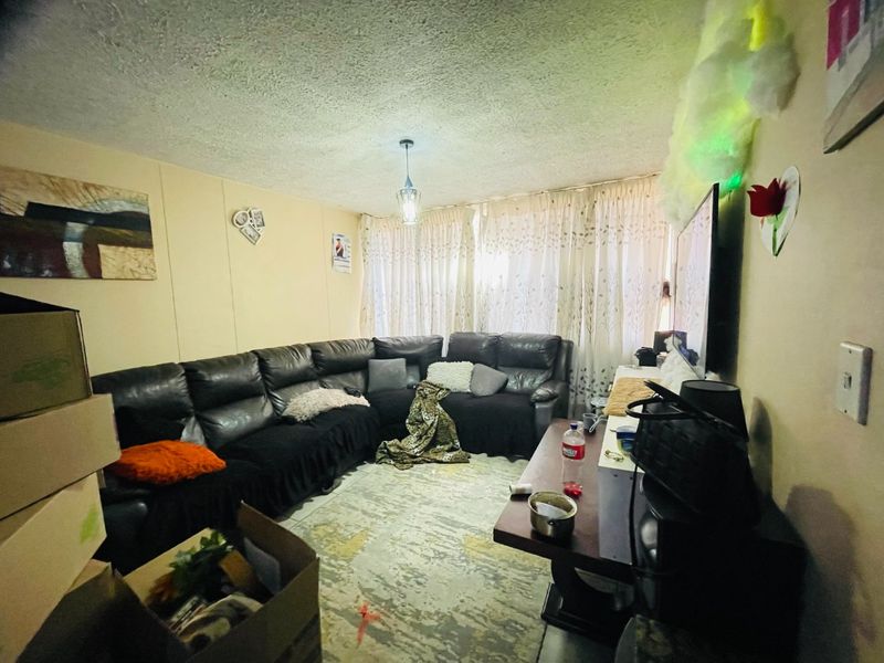A living room space featuring textured ceilings and window treatments, currently utilized as a lounge area.