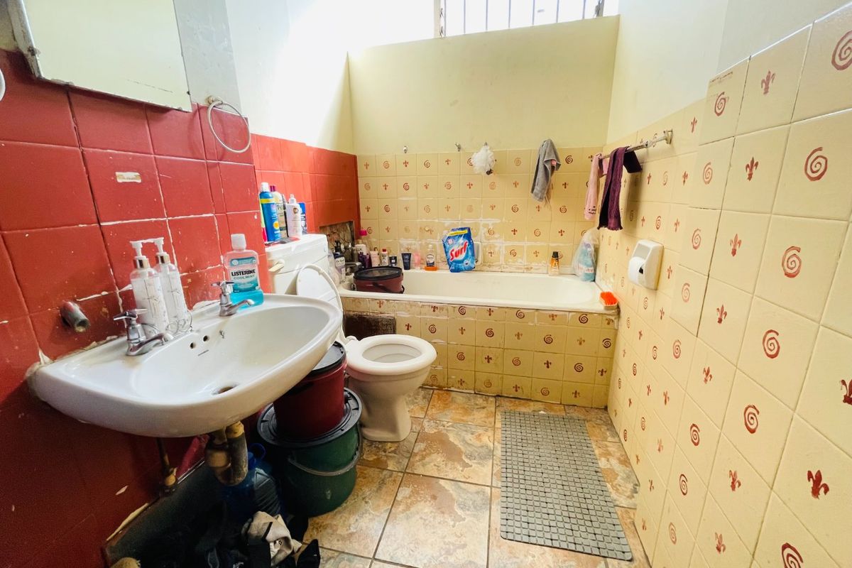 A dated bathroom featuring a pedestal basin, bathtub, and toilet with original ceramic tiling. The space requires renovation to update finishes and improve functionality.