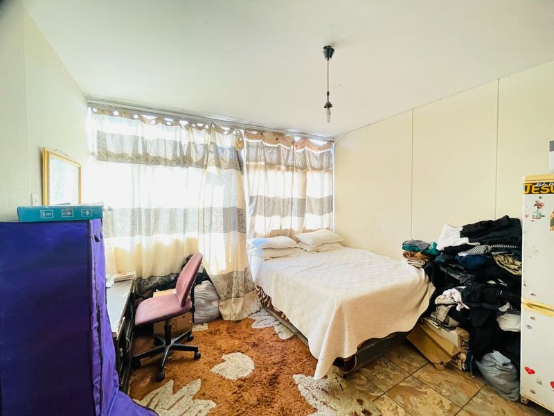 A bedroom featuring tiled flooring and a large window, requiring cosmetic updates to improve the overall condition and appeal of the space.
