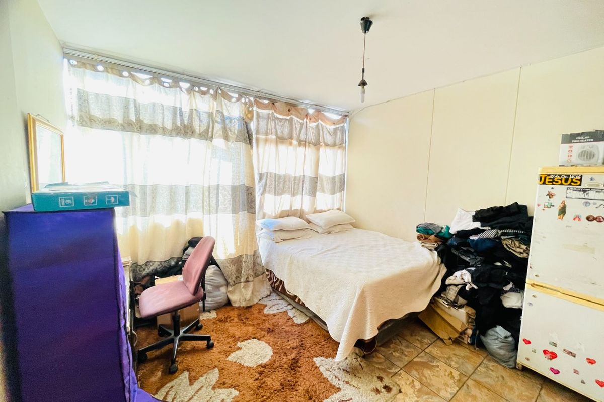 A bedroom featuring tiled flooring and a large window, providing natural light. The space is ready for a refresh to enhance its appeal.