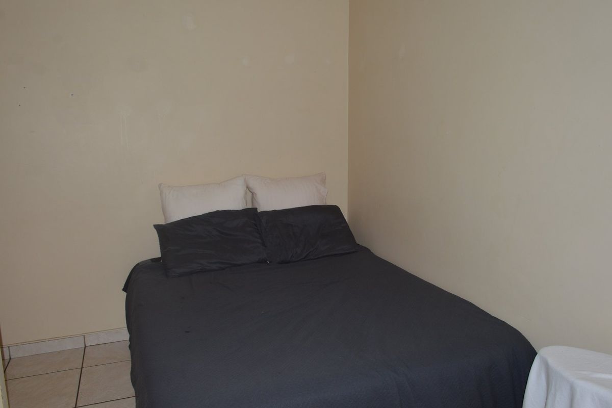 A compact bedroom featuring tiled flooring and plain walls, requiring cosmetic updates to improve the overall aesthetic and finish.