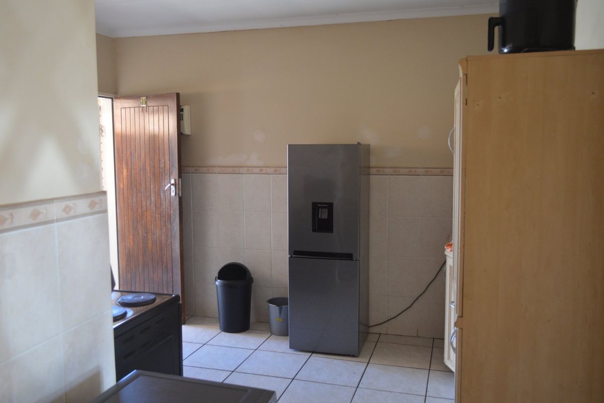 A functional kitchen area featuring tiled flooring and wall splashbacks, requiring minor cosmetic updates to the wall finishes and door.