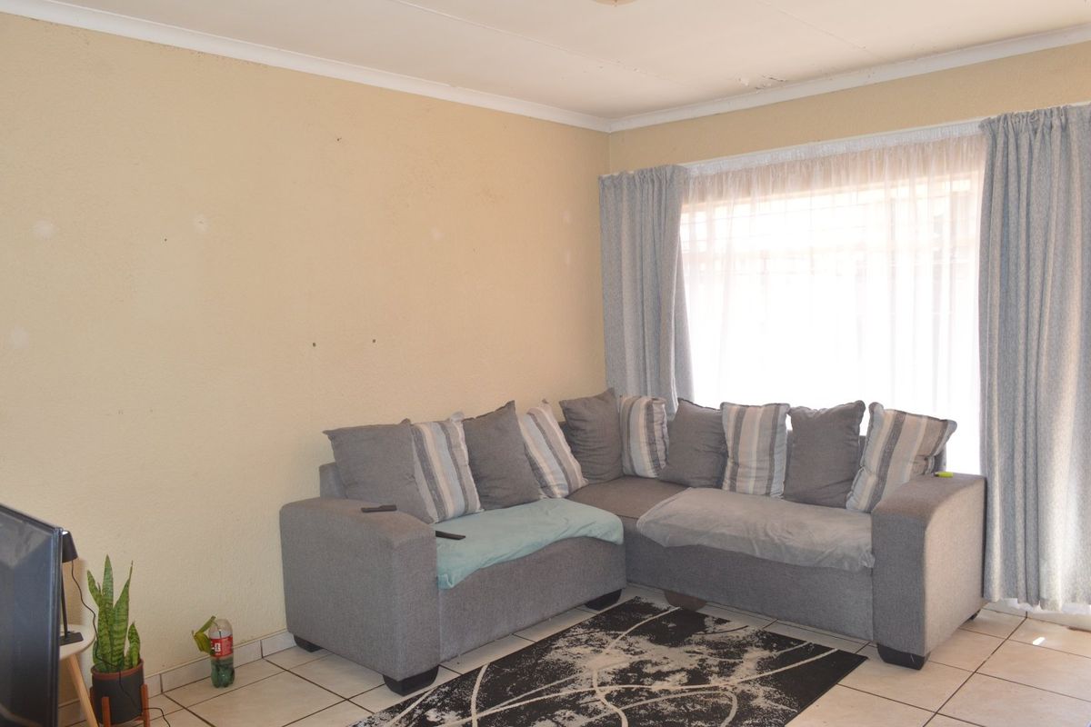 A living room featuring tiled flooring and coved ceilings, currently showing signs of wear including ceiling damage.