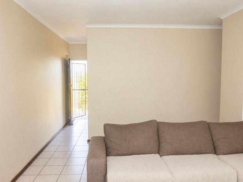 A neutrally painted living room featuring tiled flooring and a security gate leading to the exterior.