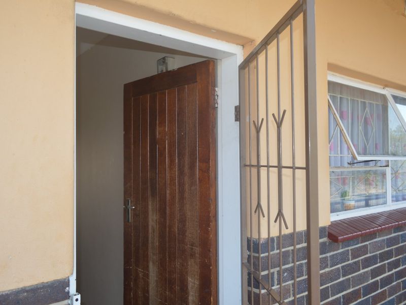 Exterior view of the apartment entrance featuring a solid timber door, security gate, and brick facade detailing.