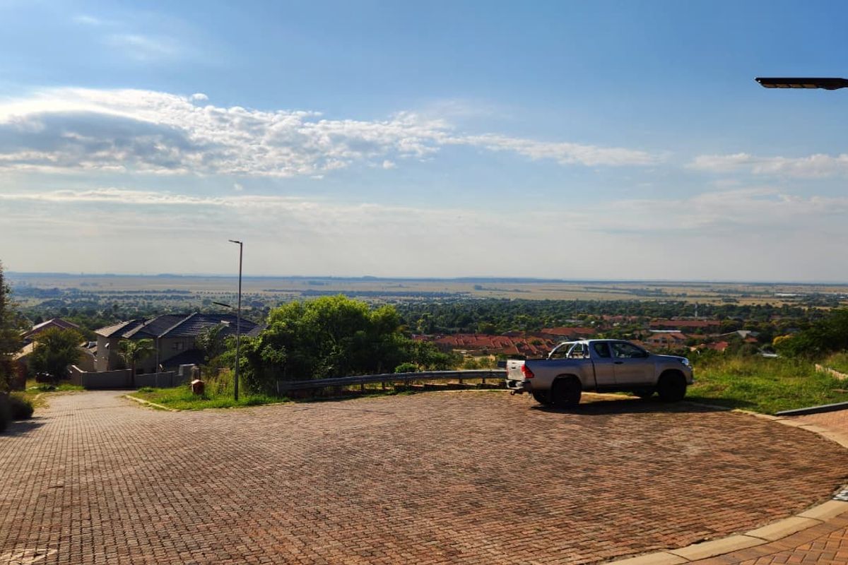 An elevated view overlooking a residential neighborhood and surrounding landscape from a paved driveway area.