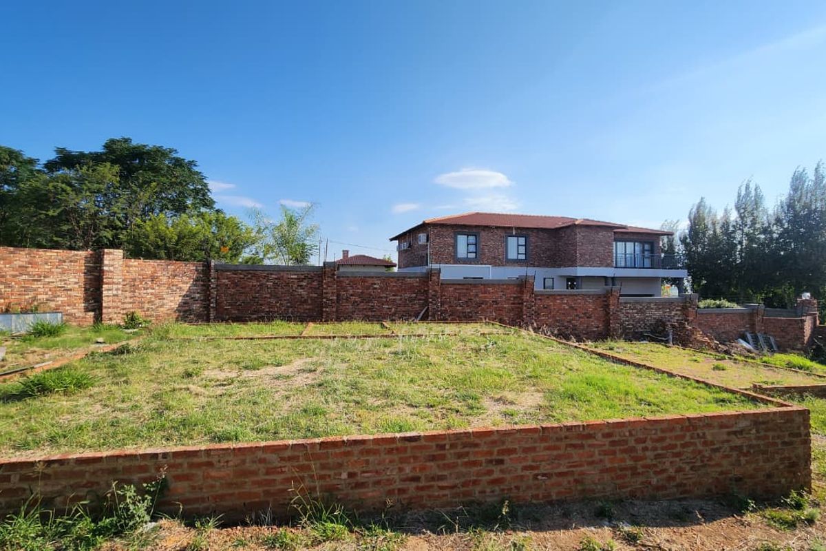 A vacant residential plot featuring a brick foundation and perimeter wall, offering a clear space for future development.