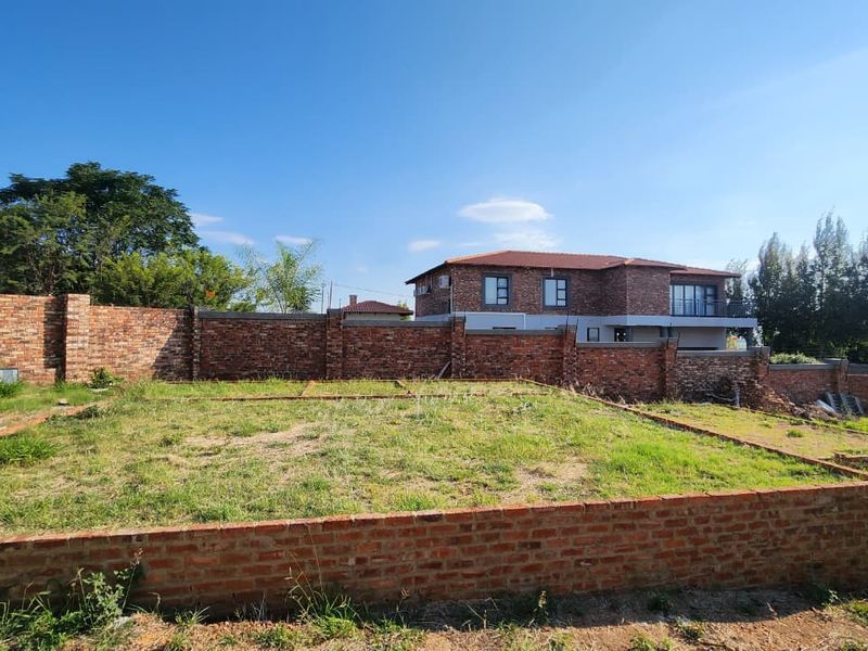 A vacant residential plot featuring a brick foundation and perimeter wall, offering a clear space for future development.