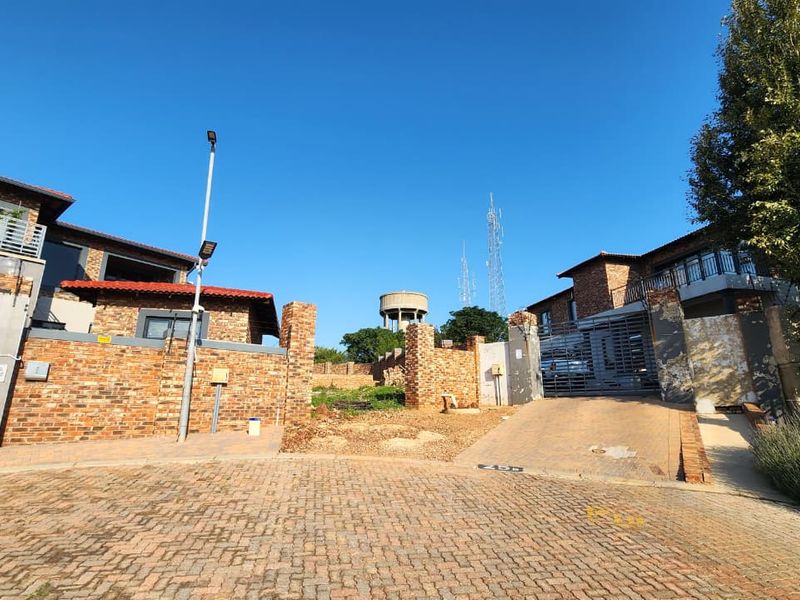 Front view of the residential property showing the paved driveway, brick boundary walls, and gated entrance access.
