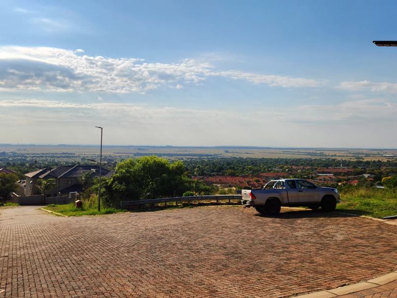An elevated view overlooking a residential neighborhood and surrounding landscape from a paved driveway area.