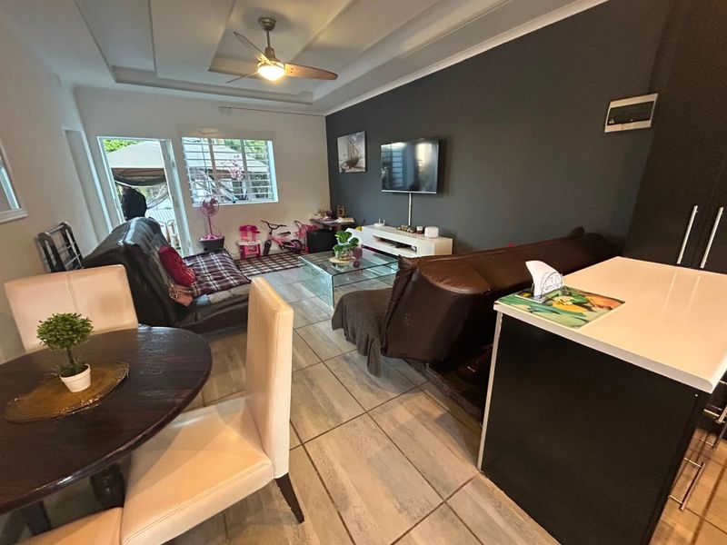 Open-plan living and dining area featuring tiled flooring, a recessed ceiling with a fan, and direct access to an outdoor space.