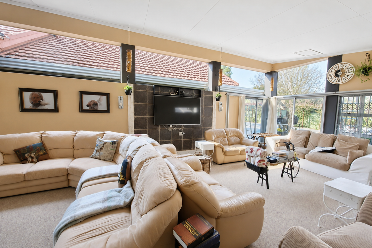 Spacious living room featuring a tiled feature wall, high clerestory windows, and large sliding glass doors providing ample natural light.