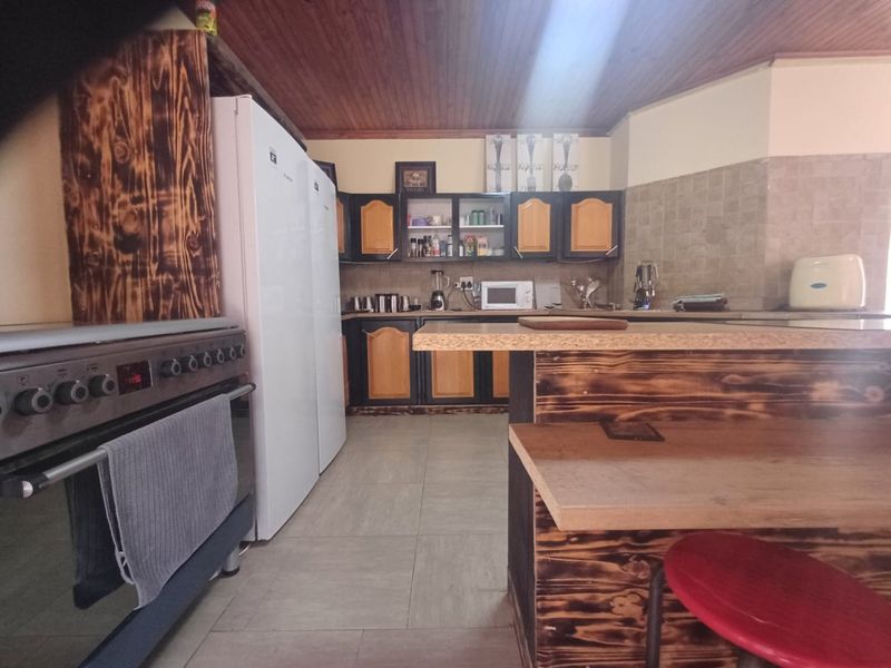 A functional kitchen featuring built-in cabinetry, a tiled backsplash, a timber ceiling, and a breakfast bar with a freestanding stove.
