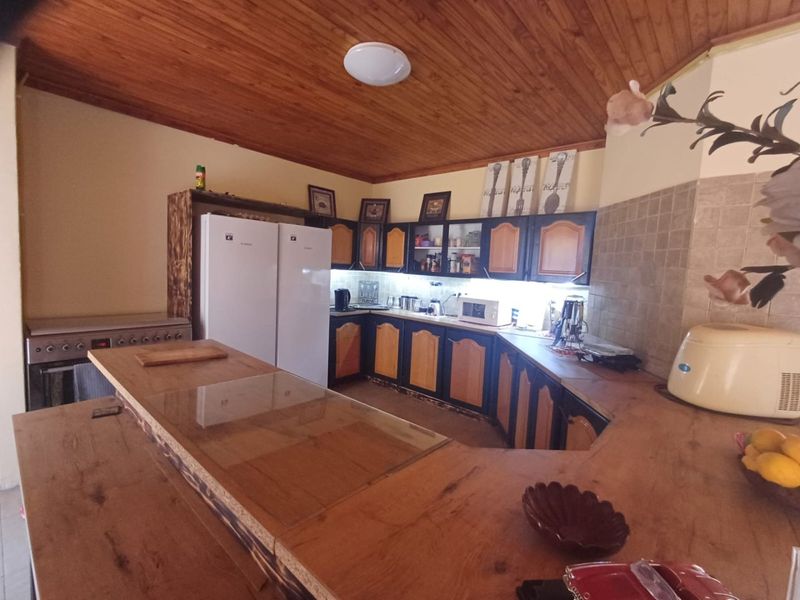 A functional kitchen featuring wooden ceiling paneling, extensive built-in cabinetry, a tiled backsplash, and a spacious breakfast bar counter.
