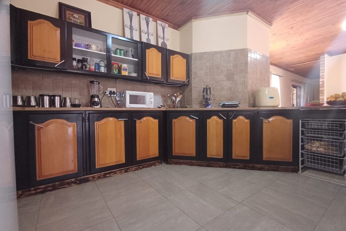 A functional kitchen featuring two-tone built-in cabinetry, tiled backsplash, and a timber ceiling, offering a classic aesthetic with potential for modern updates.