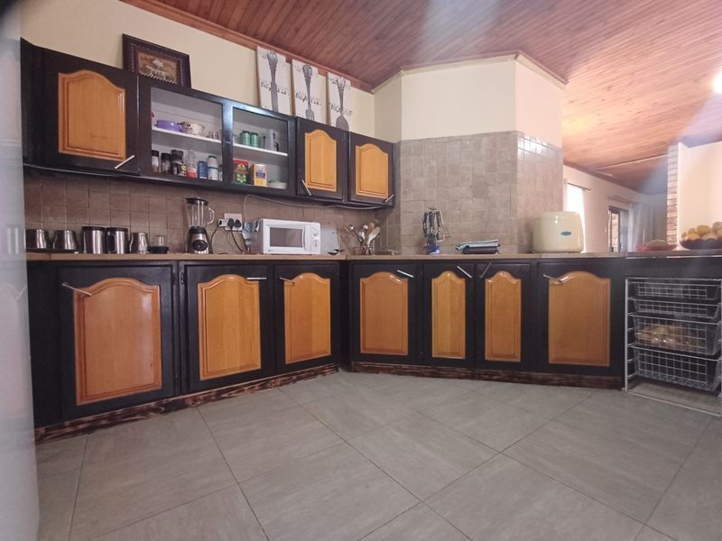 A functional kitchen featuring two-tone built-in cabinetry, tiled backsplash, and a timber ceiling, offering a classic aesthetic with potential for modern updates.