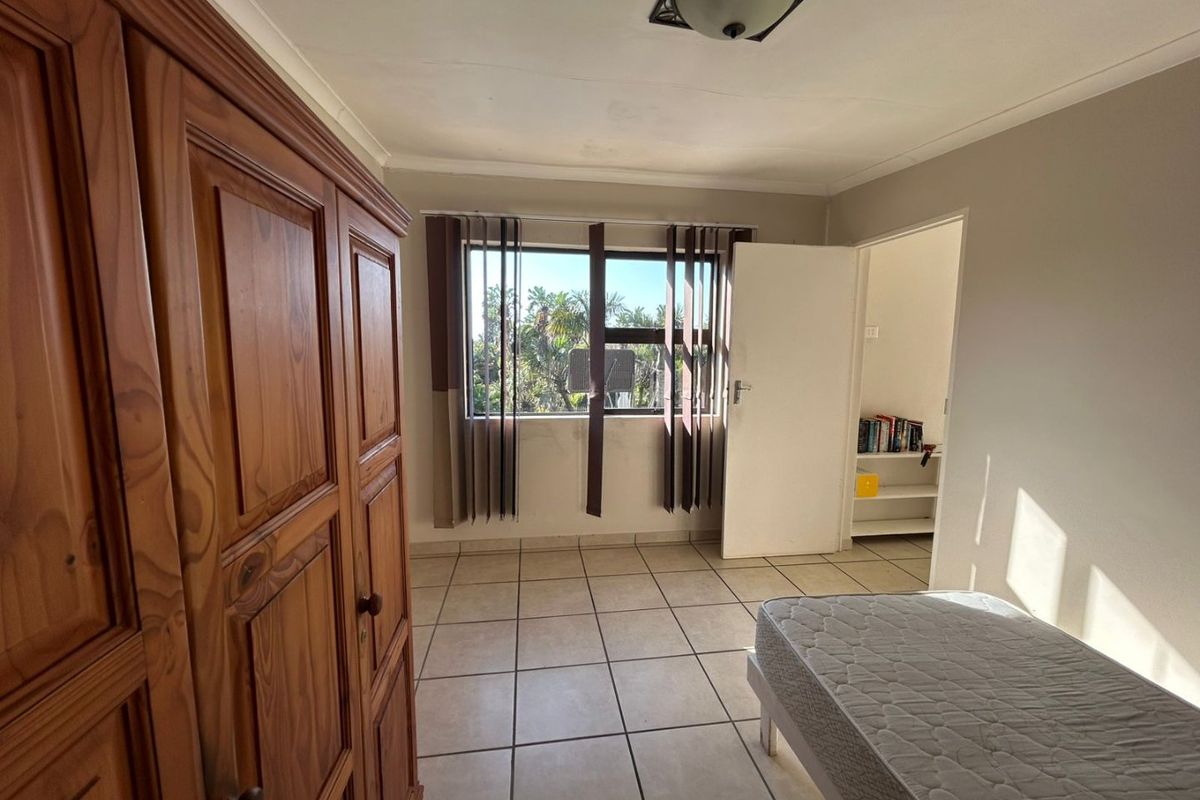 A bedroom featuring tiled flooring, built-in shelving, and natural light, offering a functional space ready for cosmetic updates and modern styling.