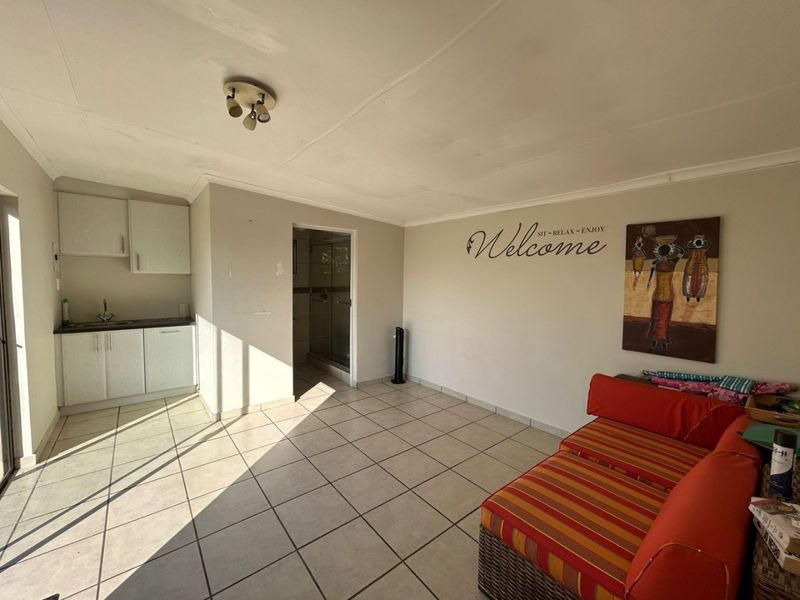 Open plan living area featuring a compact kitchenette with built-in cabinetry and an adjacent shower room with tiled flooring throughout.