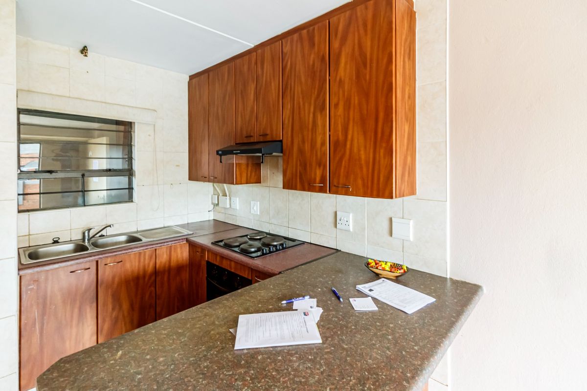 A functional kitchen featuring wooden cabinetry, laminate countertops, a built-in oven, electric hob, and a tiled backsplash.