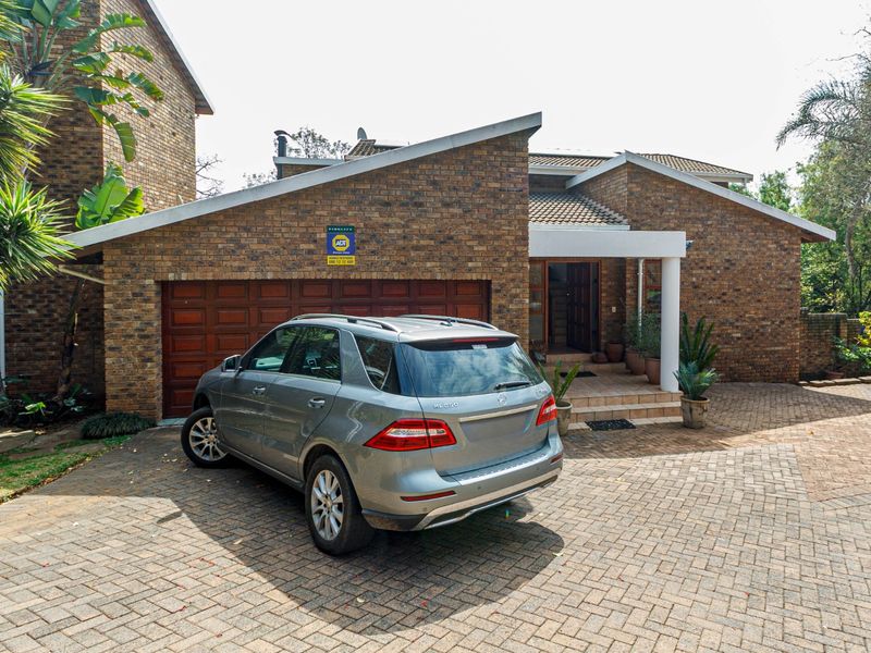 Front elevation of a brick apartment building featuring a paved driveway, double garage, and a covered entrance area.