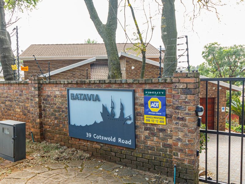 Front entrance view of the Batavia complex at 39 Cotswold Road, featuring a brick boundary wall, electric fencing, and secure gated access.