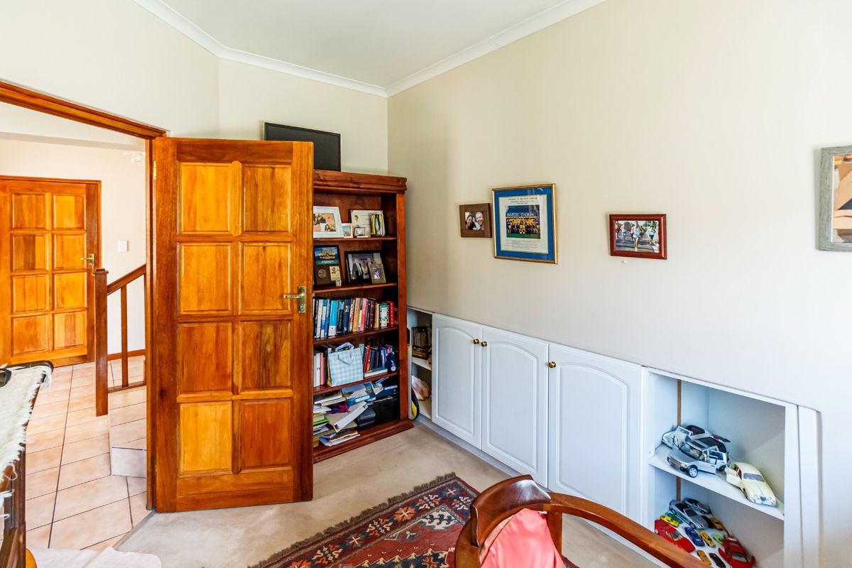 A bedroom featuring built-in white cabinetry and a solid timber door, providing functional storage space within the room.