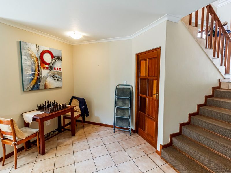 Entrance area featuring tiled flooring, a wooden staircase with carpeted treads, and a classic wooden panelled door.