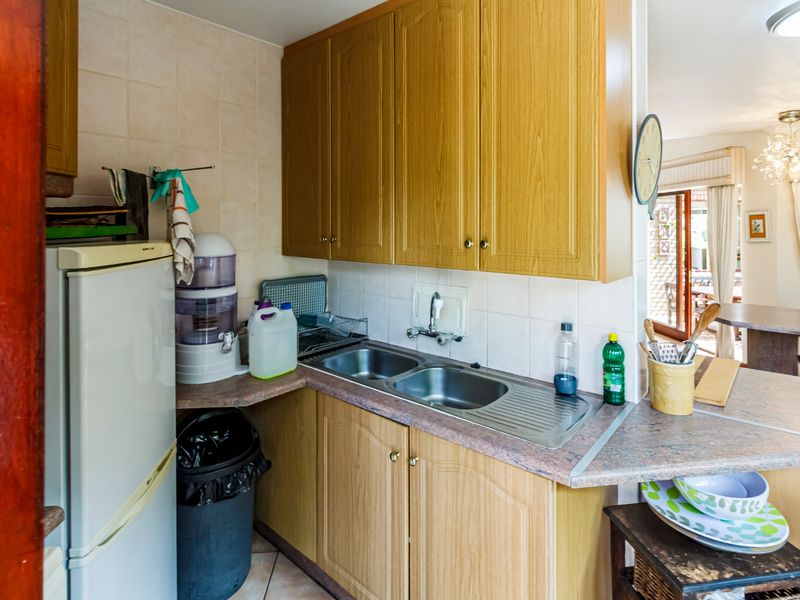 A functional kitchen area featuring laminate cabinetry, a double bowl stainless steel sink, and tiled backsplash, offering a practical layout for daily use.