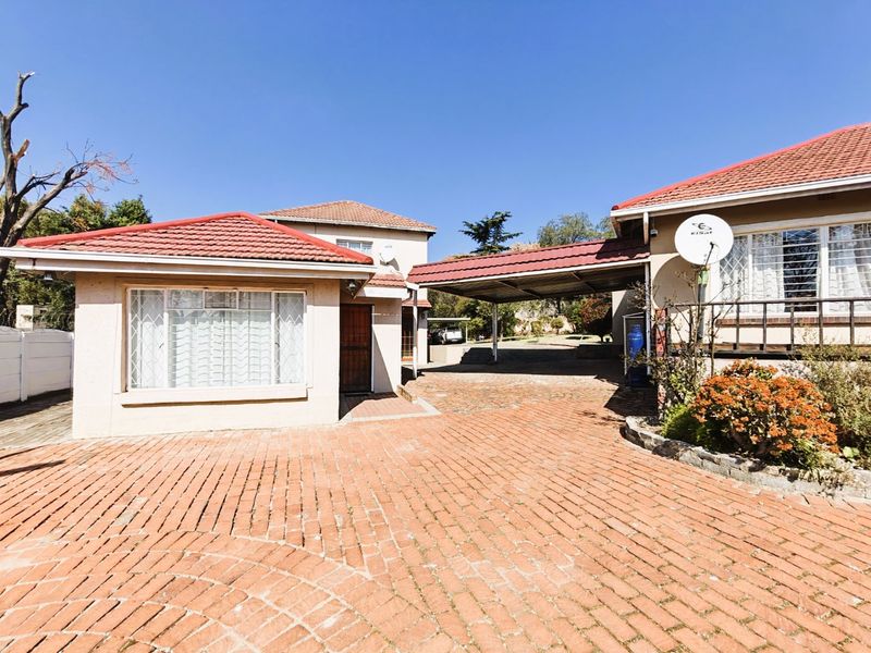 Front exterior view of the property featuring a brick-paved driveway, a covered carport, and a tiled roof structure.