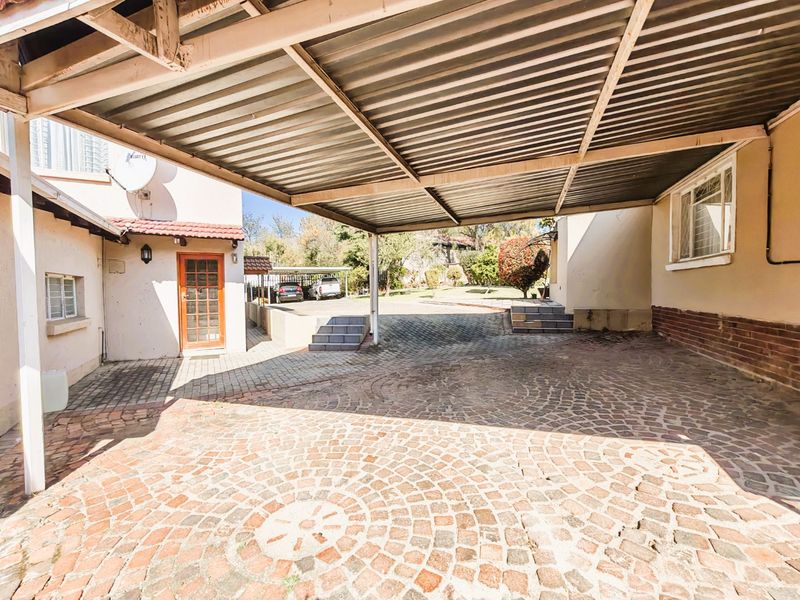 A spacious covered carport area with paved driveway, providing ample off-street parking and access to the main residence.