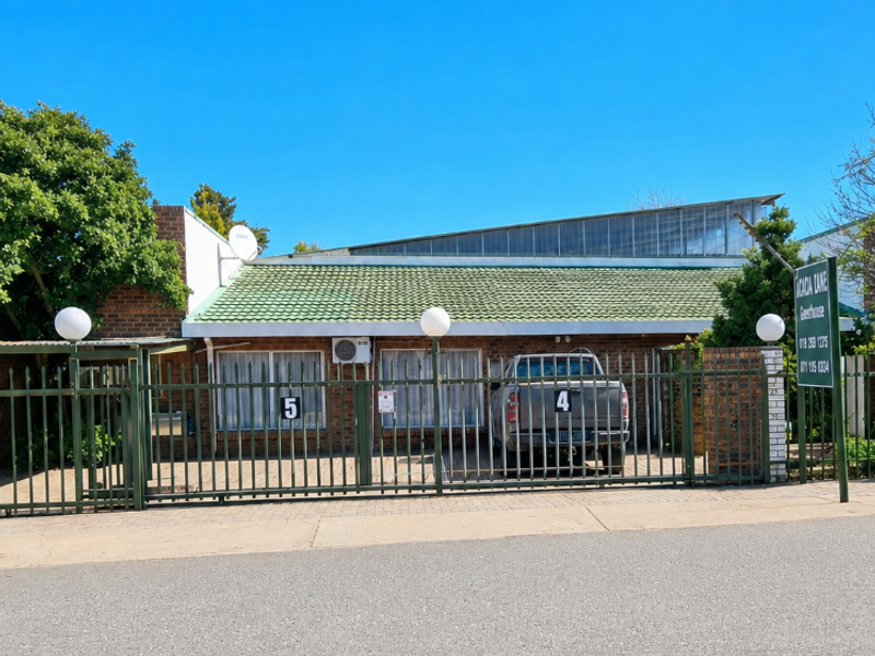 Front exterior view of a commercial property featuring a brick facade, tiled roof, and secure metal perimeter fencing.