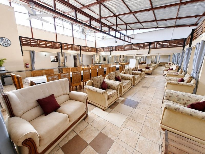 Spacious open-plan commercial area featuring tiled flooring, high exposed steel roofing with ceiling fans, and extensive mirrored wall panels.