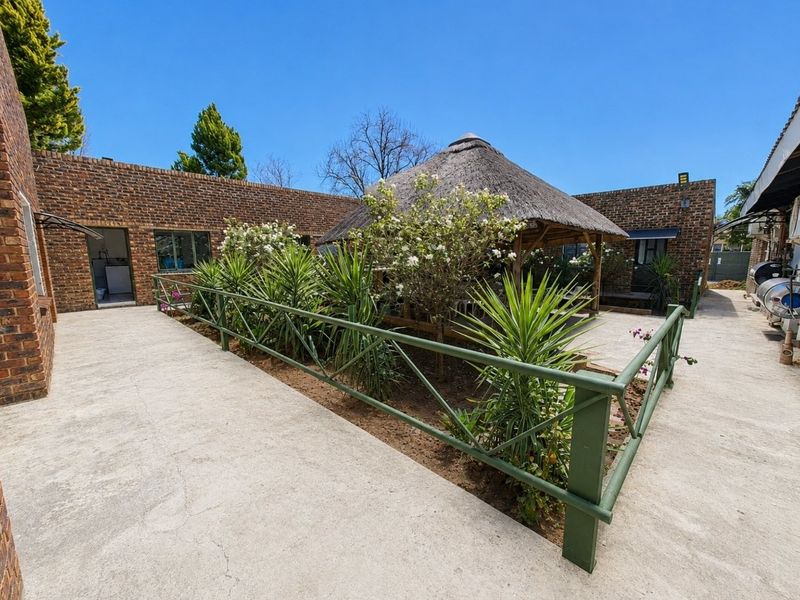 A rear courtyard area featuring a thatched gazebo, brick walling, and concrete paving, providing an outdoor space for commercial use.