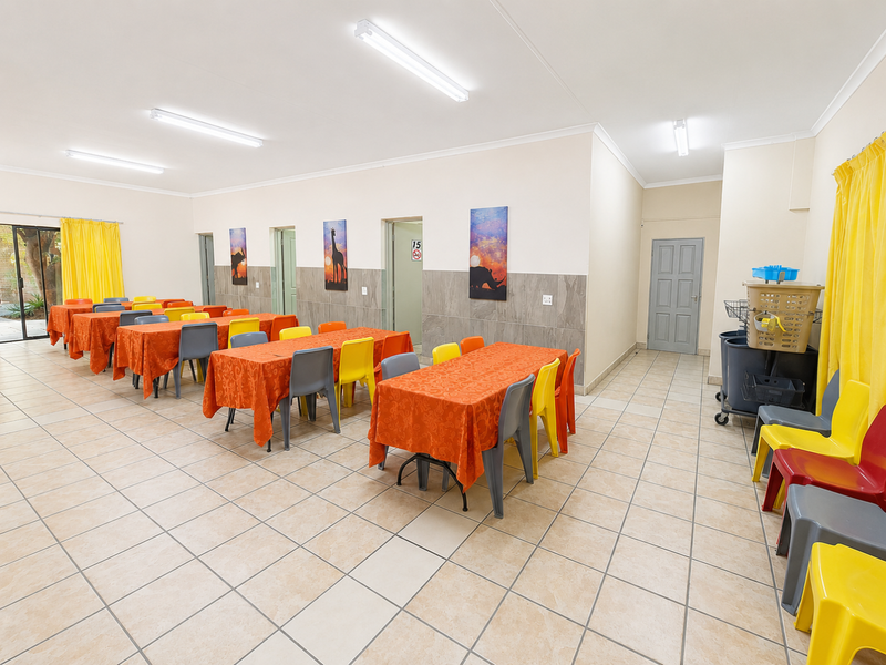 Spacious open-plan commercial area featuring tiled flooring, fluorescent lighting, and multiple access doors, suitable for a dining hall or multi-purpose function space.