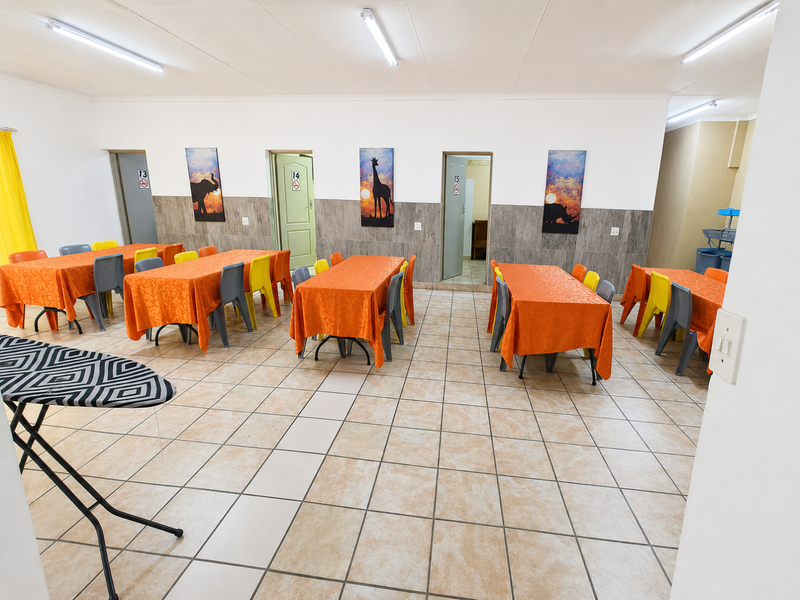 A spacious open-plan commercial area featuring tiled flooring, wall wainscoting, and multiple access points, suitable for dining or multi-purpose use.