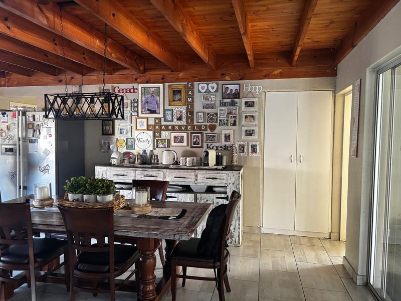 Open plan dining area featuring exposed timber beam ceilings, tiled flooring, and a built-in storage cupboard.