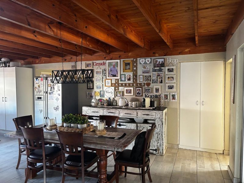 Dining area featuring exposed timber beam ceilings, tiled flooring, and built-in storage cupboards, creating a warm and functional space.