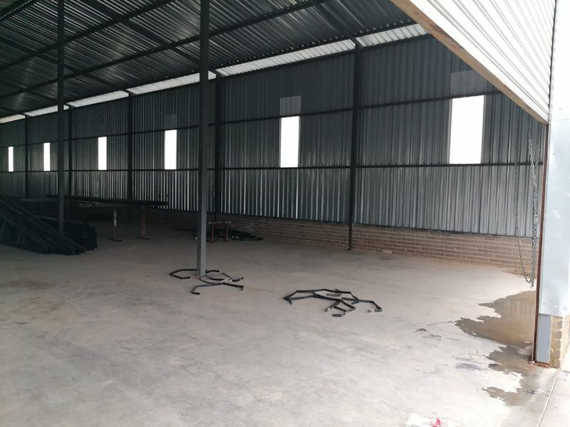 Spacious industrial utility area featuring corrugated metal walls, a metal roof, and a concrete floor, suitable for storage or workshop use.
