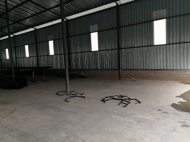 Spacious industrial utility area featuring corrugated metal walls, steel support columns, and a concrete floor, suitable for storage or workshop operations.