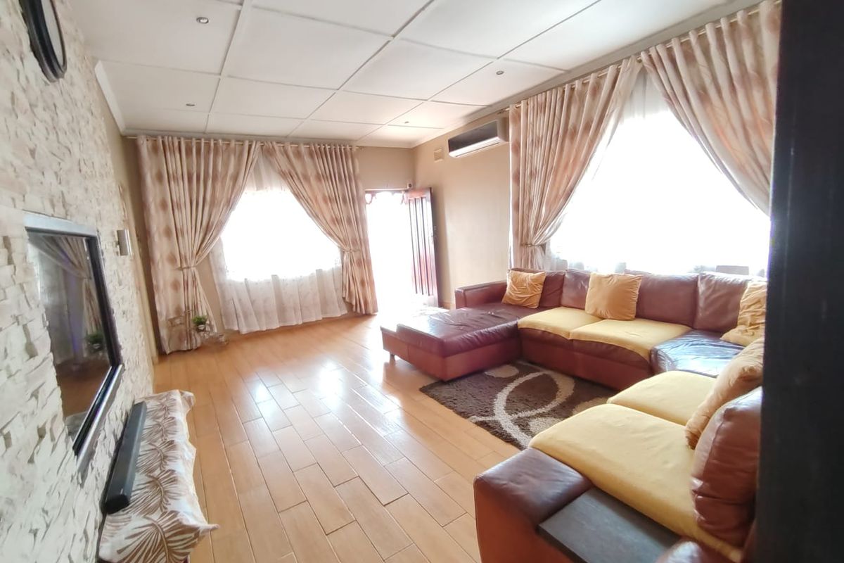 Spacious living room featuring tiled flooring, a stone-cladding feature wall, and a split-system air conditioner, offering a comfortable and functional living space.